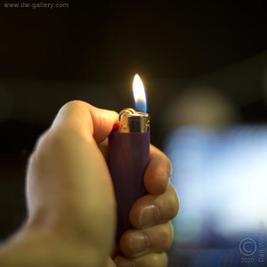 A lit lighter held in the left hand. www.dw-gallery.com